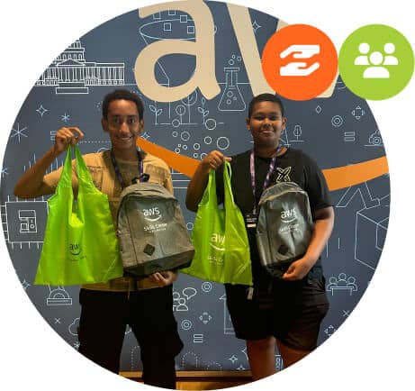 Two smiling people stand in front of an AWS-themed backdrop, holding green tote bags and gray backpacks with AWS logos. Two icons—one with arrows and one with people, representing Community Partners—are in the upper right corner.