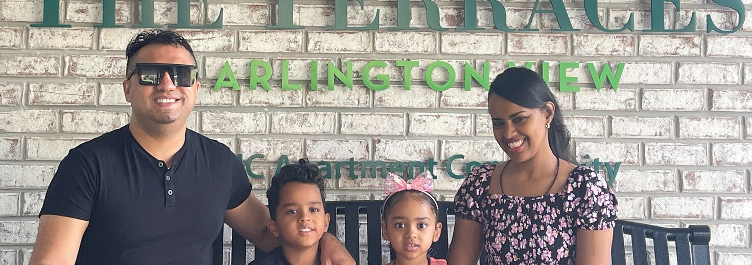 a family photo in front of an apartment building sign