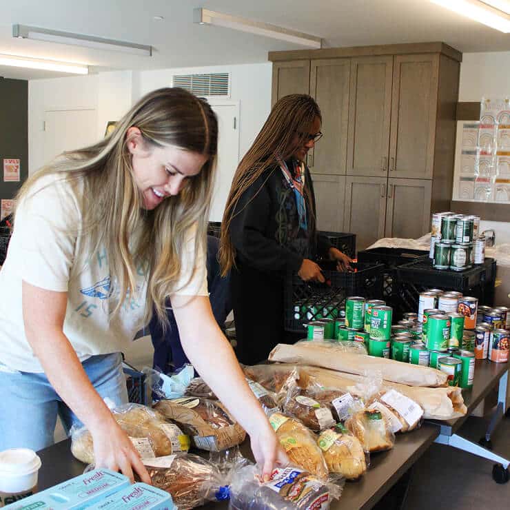 two women smiling and volunteering at a food bank